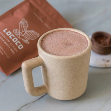 Original Spice cocoa in a stoneware mug beside the bag