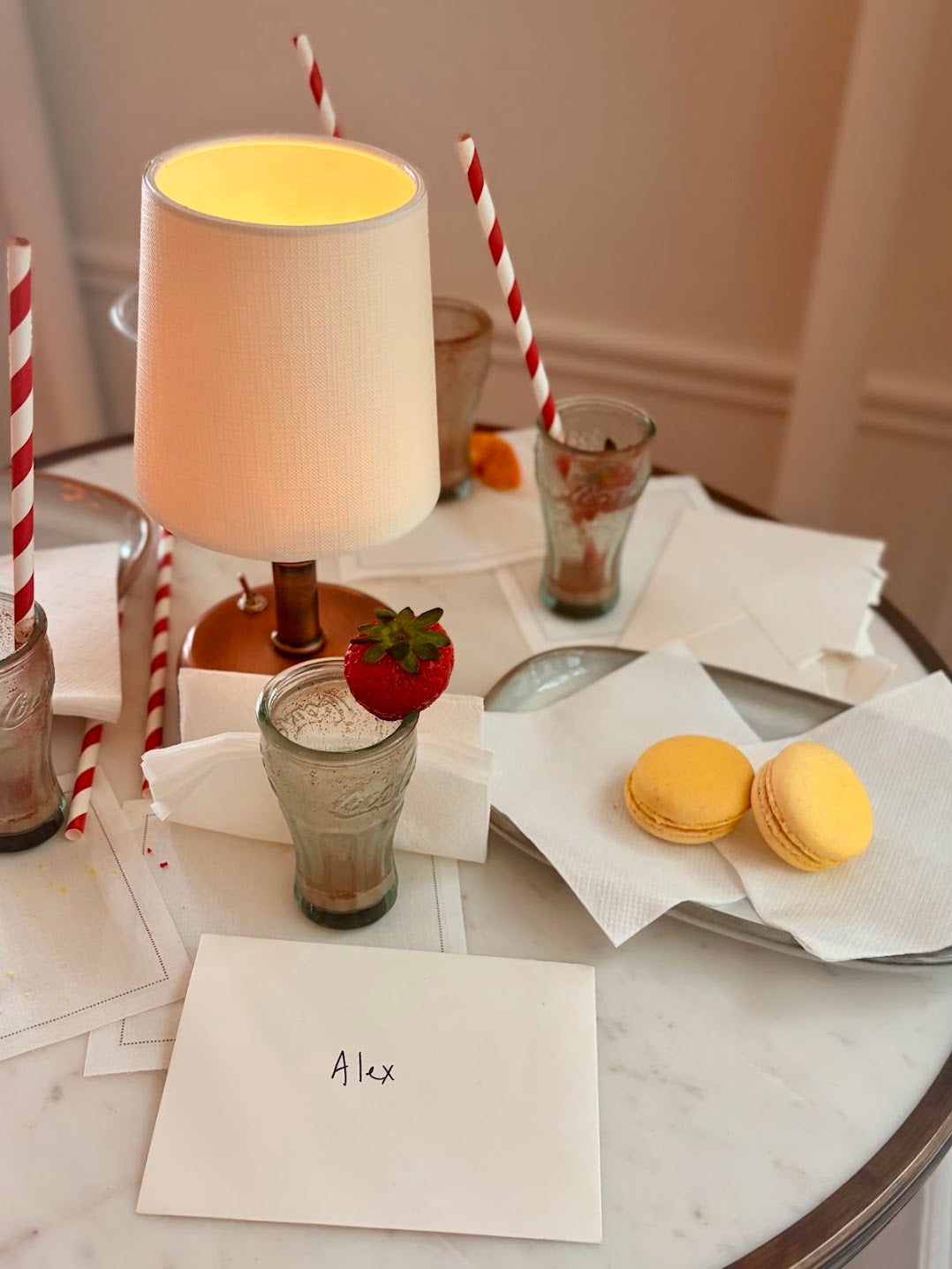 Cocoa with a fresh strawberry, macarons and a table lamp